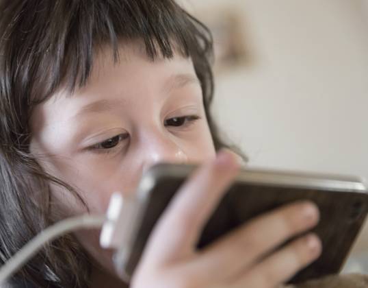 Niedliches kleines Kind, das den Bildschirm seines Smartphones genau beobachtet. Sucht nach digitalen Geräten, Kindheit und Bildung. Raum kopieren. Shallow dof Cute young child watching screen of smartphone closely. Digital device addiction, childhood and education. Copy space. Shallow dof Copyright: imageBROKER kynaxstudio ibxiqx13752893.jpg ,model released, Symbolfoto ,property released