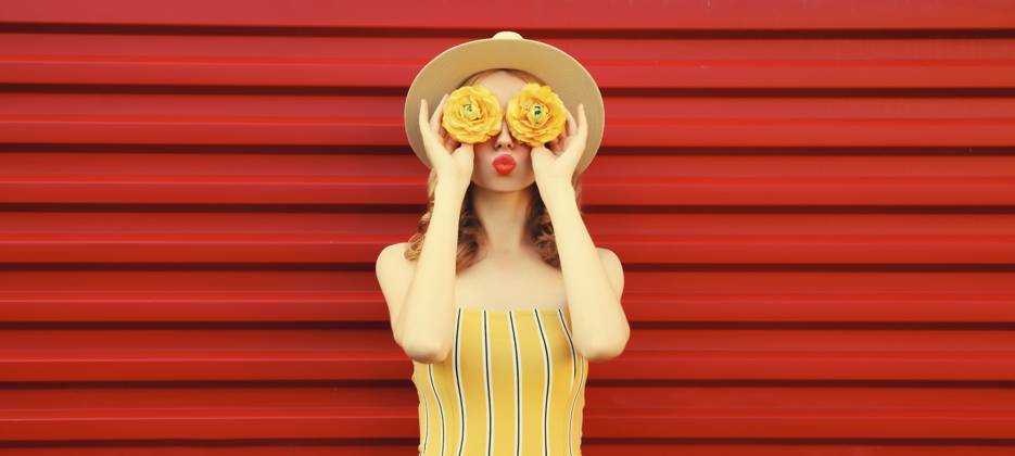 Sommer Porträt der stilvollen jungen Frau bläst Kuss mit gelben Blütenknospen auf der Suche nach etwas in runden Strohhut auf rotem Hintergrund Summer portrait of stylish young woman blowing kiss with yellow flower buds looking for something in round straw hat on red background Copyright: imageBROKER VeronikaxKorneva ibxiqx14272488.jpg ,model released, Symbolfoto ,property released