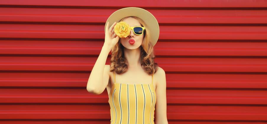 Sommer Porträt der stilvollen jungen Frau bläst Kuss mit gelben Blütenknospen auf der Suche nach etwas in runden Strohhut auf rotem Hintergrund Summer portrait of stylish young woman blowing kiss with yellow flower buds looking for something in round straw hat on red background Copyright: imageBROKER VeronikaxKorneva ibxiqx14272490.jpg ,model released, Symbolfoto ,property released