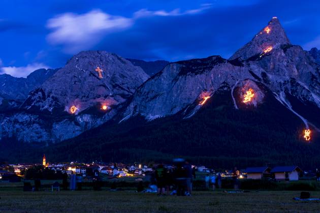 Bergfeuer Ehrwald (Mountain Fires), view to mountain Ehrwalder Sonnenspitze, visitors: Every year on the weekend around St. John s Day (summer solstice, June 21), the imposing mountain scenery surrounding the Ehrwald-Lermoos-Biberwier valley basin is transformed into a unique experience during the traditional solstice fires, with the laying out of large figures made from thousands of incendiary devices. The figures range from Christian symbolism and motifs from the flora and fauna to depictions of complex images. Additional laying out of chains of fire along the mountain ridges. Ehrwald Tiroler Zugspitz Arena Tirol, Tyrol Austria