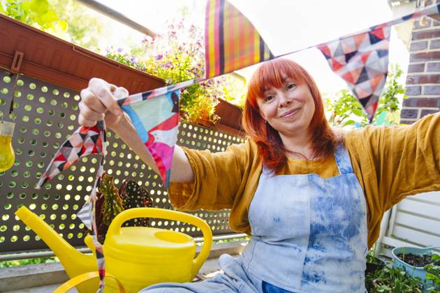 IMAGO Creative, Lifestyle, Feste im Garten #2 Smiling person decorates garden with bunting for joyful celebration at home model released, Symbolfoto property released, IHF02238