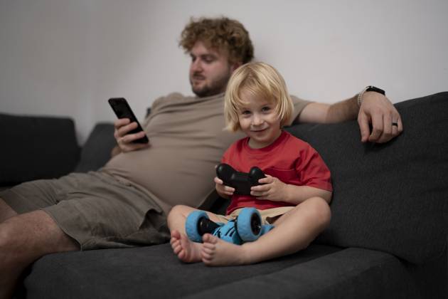 IMAGO Creative, Lifestyle, Gaming Father and son relaxing at home playing video game on sofa model released, Symbolfoto property released, OGSF00215