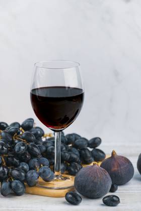 Ein Glas Rotwein mit Trauben und Feigen auf einem Holzbrett, heller Hintergrund A glass of red wine with grapes and figs on a wooden board, light-coloured background Copyright: imageBROKER LucasxSeebacher ibxlse15129451.jpg