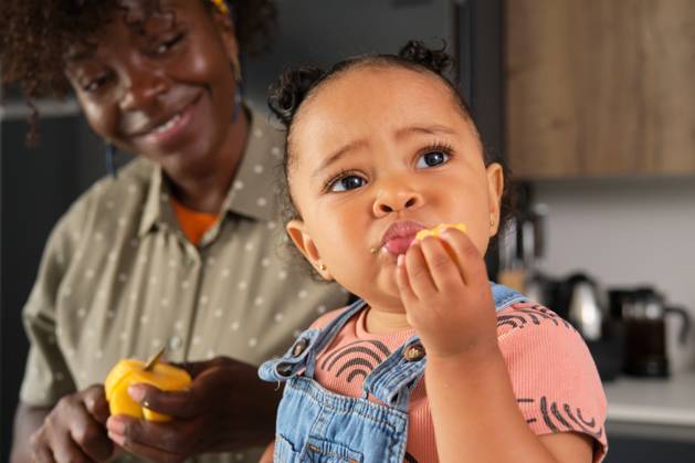 Toddler eating peach snack with mother at home kitchen model released, Symbolfoto property released, CVMF00115