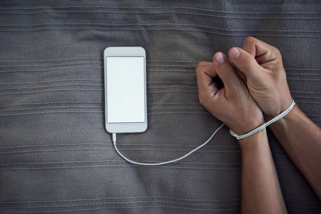Phone screen, hands tied or internet addiction with cable handcuff on bed with above mockup for control in a house. Space, app or wrist with smartphone for network, social media and web manipulation Phone screen, hands tied or internet addiction with cable handcuff on bed with above mockup for control in a house. Space, app or wrist with smartphone for network, social media and web manipulation., model released, , 60345046.jpg RECORD DATE NOT STATED