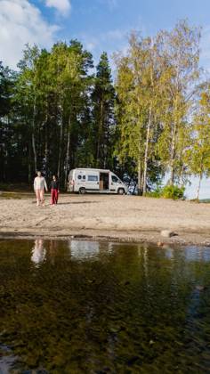 Einen ruhigen Tag am Saimaa-See in Finnland mit einem Wohnmobil und der Natur genießen Two individuals stroll along the sandy shore of Lake Saimaa in Finland, with a camper van parked nearby. Vibrant greenery surrounds the serene waters, creating a tranquil atmosphere. (License=RF) ,model released, Symbolfoto Copyright: xZoonar.com FokkexBaarssenx 24051661 ,model released, Symbolfoto ,property released