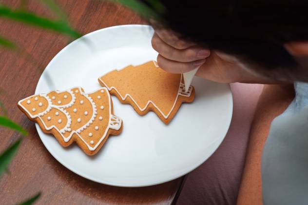 IMAGO Creative, Weihnachten, Food, Backen, Lebkuchen Verzieren von selbstgebackenen Lebkuchen in Form von Weihnachtsbäumen. Hand-piping white icing onto Christmas tree-shaped gingerbread cookies. (License=RF) Copyright: xZoonar.com AndriixAbryutinx 24056052