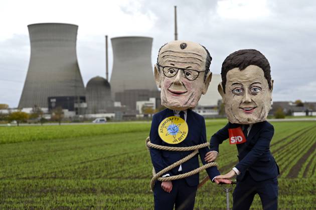 The cooling towers of the nuclear power plant in Gundremmingen before the demolition Demonstrators wearing masks of Federal Chancellor Friedrich Merz CDU and politician Lars Klingbeil SPD pose an Copyright: xDwixAnoraganingrumx