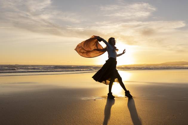 A woman is dancing on the beach with a scarf in her hand A woman is dancing on the beach with a scarf in her hand. The sky is orange and the sun is setting, model released, , 60777262.jpg RECORD DATE NOT STATED