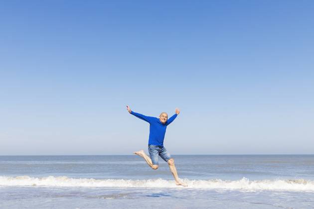 Man jumping for joy on the beach with blue sky and sea model released, Symbolfoto, GWF08396