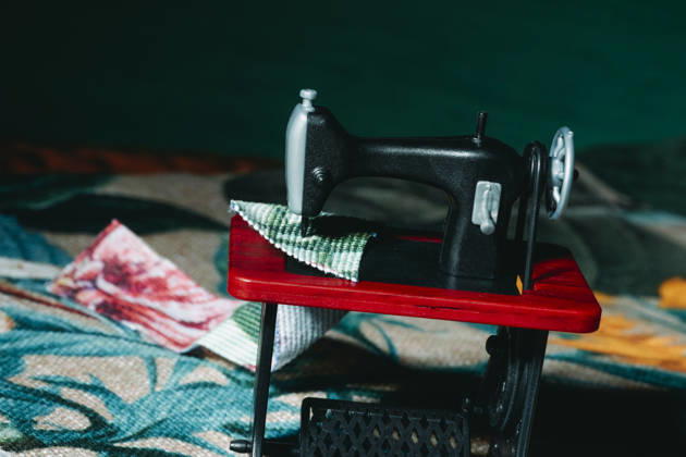 IMAGO Creative, Lifestyle, Freizeit, Hobby, Handarbeit, Nähen #2 Toy sewing machine working with fabric on bold red tabletop, JMYF00185