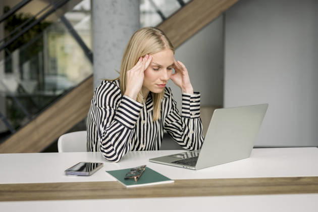 Stressed businesswoman working on laptop at modern office desk model released, Symbolfoto property released, FLMZF01870