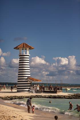 Tourists enjoying dominican republic beach with iconic striped lighthouse Bayahibe, Dominican Republic 1 January 2025: Tourists relaxing on the beach near a black and white striped lighthouse in dominicus, dominican republic, a popular caribbean destination, 64091164.jpg RECORD DATE NOT STATED
