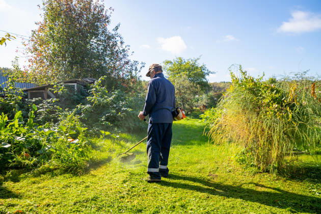Senior man uses grass trimmer to cut overgrown lawn in his backyard Chelyabinsk, Chelyabinsk Oblast, Russia CR_STCJ260106-1921652-01 ,model released, Symbolfoto