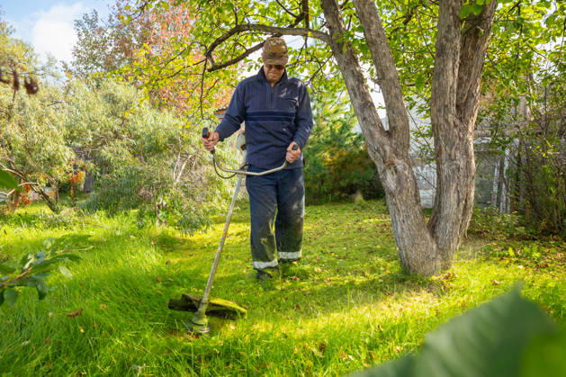 Senior man uses grass trimmer to cut overgrown lawn in his backyard Chelyabinsk, Chelyabinsk Oblast, Russia CR_STCJ260106-1921673-01 ,model released, Symbolfoto