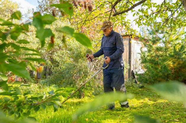 Senior man uses grass trimmer to cut overgrown lawn in his backyard Chelyabinsk, Chelyabinsk Oblast, Russia CR_STCJ260106-1921678-01 ,model released, Symbolfoto