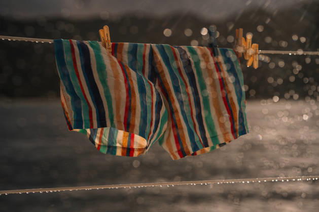 IMAGO Creative, Jahreszeit Sommer, Regen, Sommerregen Striped Men?s Swim Shorts Hanging on Catamaran Rail in Rain Victoria, Mont Fleuri, Seychelles CR_NMDM260127-1951716-01