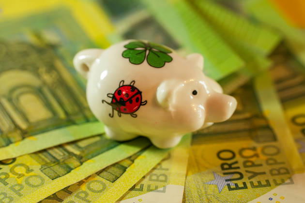 Miniature Piggy bank at 100 Euro Banknotes in the Business world as symbol for Happiness and Prosperity 1133302125
