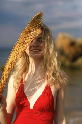 Schöne junge Frau mit blonden Haaren posiert am Strand in einem roten Bikini Beautiful young woman with blond hair posing on the beach in a red bikini. She enjoys the wind, smiles. In her hands is a palm leaf, a figured shadow on her face on a summer day. High quality photo. (License=RF) ,model released, Symbolfoto Copyright: xZoonar.com HannaxNikulnikovax 23896503 ,model released, Symbolfoto ,property released