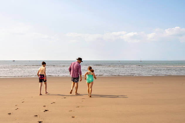 back view of single father with kids walking on beach to the sea. Wales, England, United Kingdom R_JNDO260222-1935004-01 ,model released, Symbolfoto