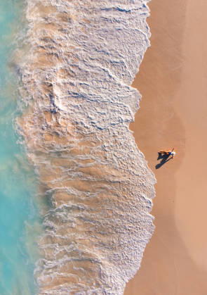 Aerial view of woman on sandy beach as ocean waves roll in. Grace Bay, Caicos Islands, Turks and Caicos Islands CR_DOHO260224B-1973403-01 ,model released, Symbolfoto