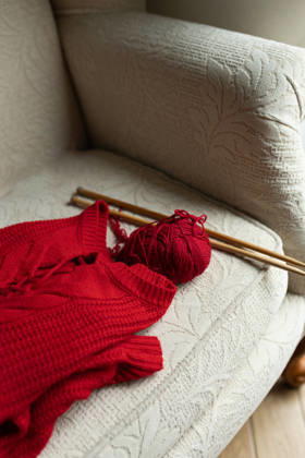Knitting hobby with red sweater on comfortable armchair A plush armchair displays a vibrant red sweater, knitting needles, and yarn, capturing the essence of a cozy knitting hobby Model Released Nastyaofly_ID33665_1171508_003 Copyright: xNastyaoflyx RECORD DATE NOT STATED