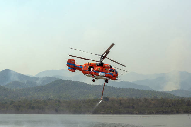 March 27, 2026, Chiang Mai, Thailand: A helicopter performs water pickup operations over a reservoir in Chiang Mai, northern Thailand, as part of aerial firefighting efforts against ongoing wildfires. A KA-32 helicopter from the Department of Disaster Prevention and Mitigation skims the water surface to collect water before heading to fire-affected forest areas amid hazy conditions caused by smoke and rising PM2.5 pollution. Chiang Mai Thailand  - ZUMAs197 20260327_aaa_s197_308 Copyright: xPongmanatxTasirix