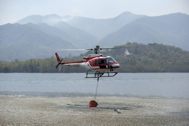 March 27, 2026, Chiang Mai, Thailand: A helicopter performs water pickup operations over a reservoir in Chiang Mai, northern Thailand, as part of aerial firefighting efforts against ongoing wildfires. An AS350 helicopter from the Ministry of Natural Resources and Environment skims the water surface to collect water before heading to fire-affected forest areas amid hazy conditions caused by smoke and rising PM2.5 pollution. Chiang Mai Thailand  - ZUMAs197 20260327_aaa_s197_312 Copyright: xPongmanatxTasirix