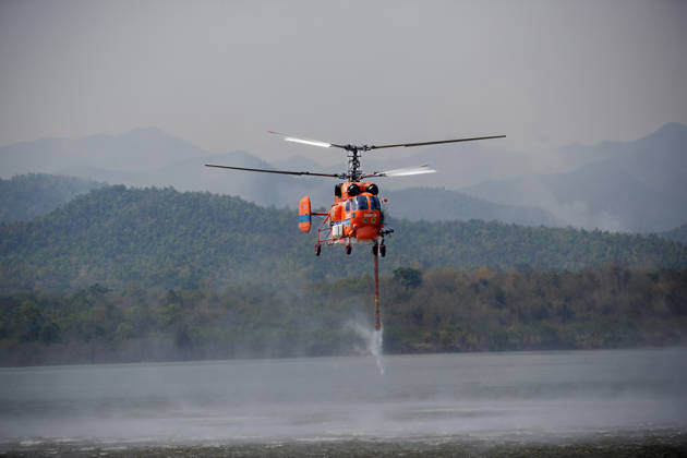 March 27, 2026, Chiang Mai, Thailand: A helicopter performs water pickup operations over a reservoir in Chiang Mai, northern Thailand, as part of aerial firefighting efforts against ongoing wildfires. A KA-32 helicopter from the Department of Disaster Prevention and Mitigation skims the water surface to collect water before heading to fire-affected forest areas amid hazy conditions caused by smoke and rising PM2.5 pollution. Chiang Mai Thailand  - ZUMAs197 20260327_aaa_s197_321 Copyright: xPongmanatxTasirix