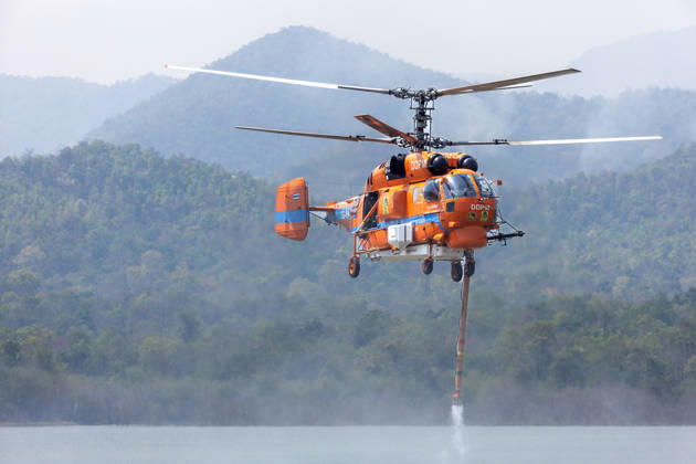 March 27, 2026, Chiang Mai, Thailand: A helicopter performs water pickup operations over a reservoir in Chiang Mai, northern Thailand, as part of aerial firefighting efforts against ongoing wildfires. A KA-32 helicopter from the Department of Disaster Prevention and Mitigation skims the water surface to collect water before heading to fire-affected forest areas amid hazy conditions caused by smoke and rising PM2.5 pollution. Chiang Mai Thailand  - ZUMAs197 20260327_aaa_s197_342 Copyright: xPongmanatxTasirix