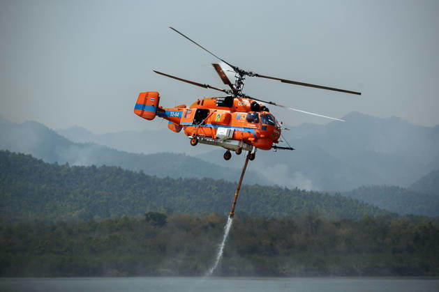 March 27, 2026, Chiang Mai, Thailand: A helicopter performs water pickup operations over a reservoir in Chiang Mai, northern Thailand, as part of aerial firefighting efforts against ongoing wildfires. A KA-32 helicopter from the Department of Disaster Prevention and Mitigation skims the water surface to collect water before heading to fire-affected forest areas amid hazy conditions caused by smoke and rising PM2.5 pollution. Chiang Mai Thailand - ZUMAs197 20260327_aaa_s197_328 Copyright: xPongmanatxTasirix
