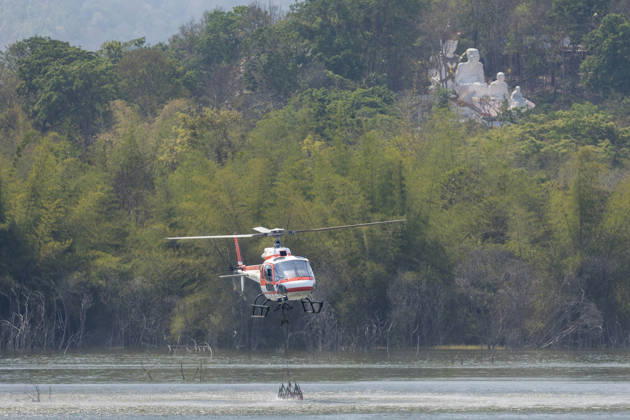 March 27, 2026, Chiang Mai, Thailand: A helicopter performs water pickup operations over a reservoir in Chiang Mai, northern Thailand, as part of aerial firefighting efforts against ongoing wildfires. An AS350 helicopter from the Ministry of Natural Resources and Environment skims the water surface to collect water before heading to fire-affected forest areas amid hazy conditions caused by smoke and rising PM2.5 pollution. Chiang Mai Thailand  - ZUMAs197 20260327_aaa_s197_379 Copyright: xPongmanatxTasirix