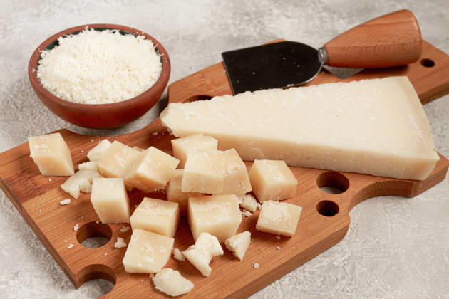 Frisch geschnittener und geriebener Käse, Parmesan, auf einem hölzernen Schneidebrett, auf rustikale Art, ohne Menschen Freshly sliced and grated cheese, parmesan cheese, Gran gusto. Grana padano. on a wooden chopping board, rustic style, no people (License=RF) Copyright: xZoonar.com GalinaxDidebashvilix 24938236