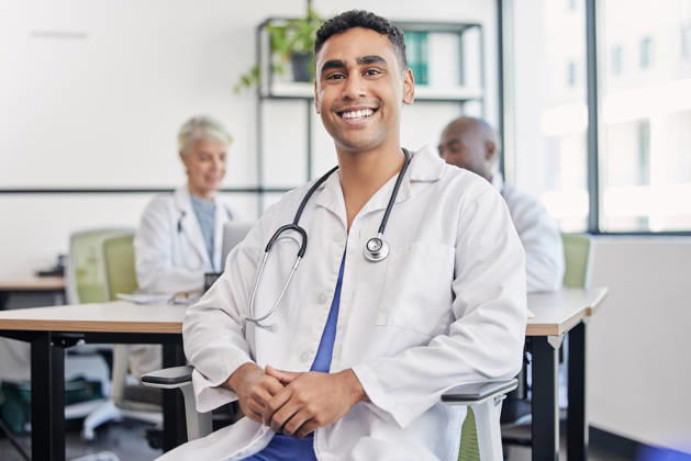 Young doctor, man and portrait at hospital desk with smile for healthcare, planning and teamwork. Professional leader, doctors and expert in health, wellness and happy in clinic with group at table. (License=RF) ,model released, Symbolfoto  Copyright: xZoonar.com YurixArcursxpeopleimages.comx 19870270 ,model released, Symbolfoto ,property released