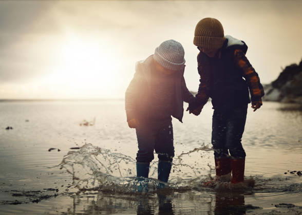 Beach, sunset and silhouette of children in water splash together, holding hands and playing in waves. Fun, holiday and brothers, happy in boots on ocean vacation, jumping in sea on winter evening (License=RF) ,model released, Symbolfoto Copyright: xZoonar.com YurixArcursxpeopleimages.comx 20001147 ,model released, Symbolfoto ,property released