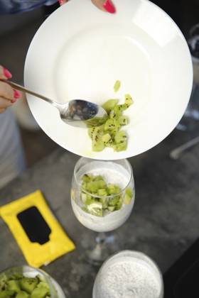 Die Person gibt Kiwi Stücke in das Dessertglas auf dem Tisch, wobei einige Zutaten an einem sonnigen Tag in der Nähe sind Person adds kiwi pieces to dessert glass on table with some ingredients nearby during a sunny day Copyright: imageBROKER AlekseixIsachenko ibxaii17581688.jpg ,model released, Symbolfoto ,property released
