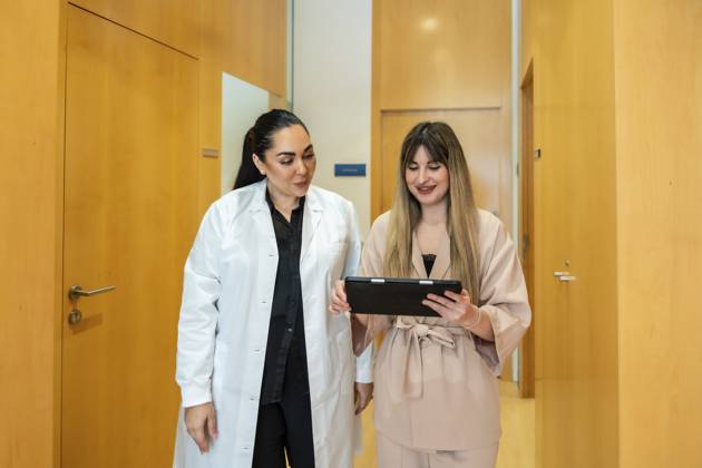 Der Arzt erklärt einem lächelnden Patienten während einer Konsultation in einem modernen ästhetischen Klinikflur mithilfe eines digitalen Tablets medizinische Daten und fördert so Vertrauen und klare Kommunikation Doctor explaining medical data to a smiling patient using a digital tablet during a consultation in a modern aesthetic clinic hallway, fostering trust and clear communication Copyright: imageBROKER UnaixHuizi ibxuhu17095931.jpg ,model released, Symbolfoto ,property released