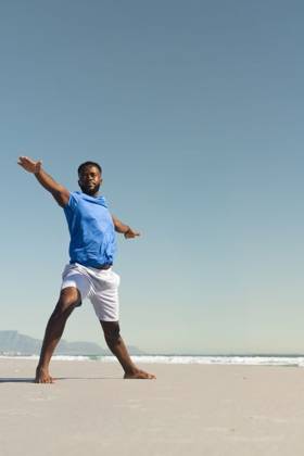 African American man standing barefoot on sandy beach at waterline wearing blue shirt white shorts, model released, property released, 27.03.2025 06:00:00, 12885004 Copyright: xIMS-260410_1xcreatorid:x331x 12885004