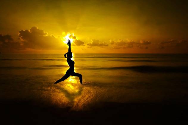 Silhouette of female doing yoga meditation during sunrise with natural golden sunlight at beach. model released Symbolfoto Copyright: xszefeix Panthermedia70087272.jpg