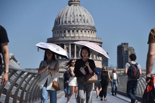 May 26, 2026, London, England, United Kingdom: People shelter from the scorching sun under umbrellas on Millennium Bridge with a view of St Paul s Cathedral as temperatures soar in the capital. The UK recorded its hottest ever day in May yesterday. London United Kingdom - ZUMAv130 20260526_zip_v130_002 Copyright: xVukxValcicx