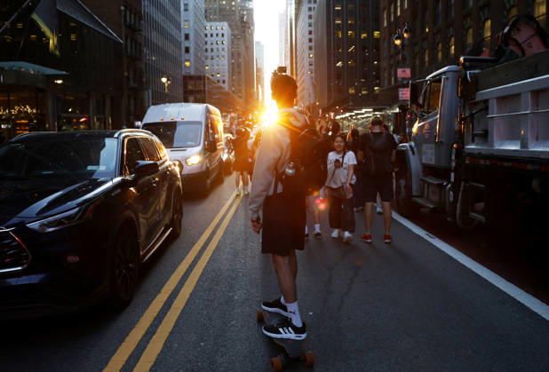 A skateboarder captures content with a cell phone while riding on 42nd street for a Manhattanhenge sunset event in New York City on Thursday, May 28, 2026. The Manhattanhenge sunset comes twice a year when the setting sun aligns precisely with Manhattan s street grid.  NYP20260528202 JohnxAngelillo