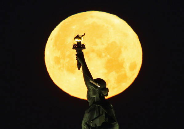 A rare Blue Moon, the second full moon to appear in the sky in a single month, sets behind the Statue of Liberty on Sunday, May 31, 2026 in New York City.  NYP20260531102 JOHNxANGELILLO
