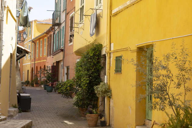 Villefranche sur Mer France 31052026 Alley in the old town of Villefranche sur Mer, Cote d Azur Côte d Azur , Southern France Colorful house facades in ocher, yellow and pink, narrow staircase alley, woman as a passer-by Departement Alpes Maritimes Villefranche sur Mer Departement Alpes Maritimes France 310526_ppb-12