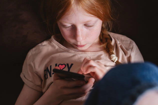 Child looking at smartphone experiencing screen addiction indoors model released, Symbolfoto property released, IHF02737