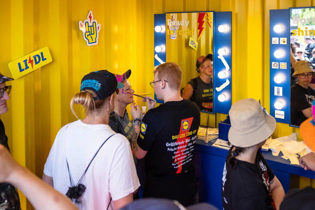 Music festival Rock im Park 2026, Nuremberg, 07 06 2026 A Lidl employee applies make-up to a festival visitor at the make-up box in the Lidl Rock Store Illuminated mirrors and yellow container optics characterize the brand appearance Nuremberg Bavaria Germany 20260607-286A8406-M4000