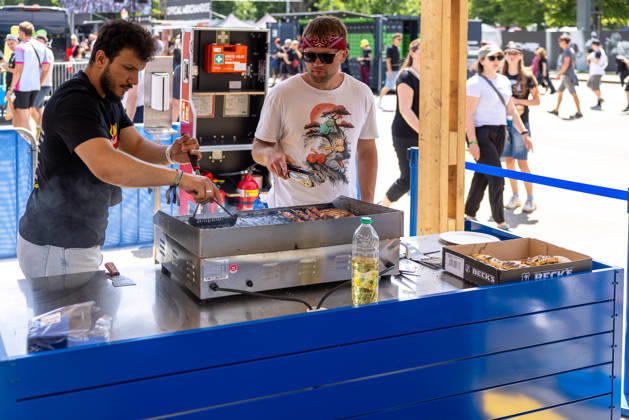 Rock im Park 2026 music festival, Nuremberg, 07 06 2026 Two employees grilling meat skewers at the Lidl BBQ station on the festival site Festival visitors can be seen in the background Nuremberg Bavaria Germany 20260607-286A8408-M4000