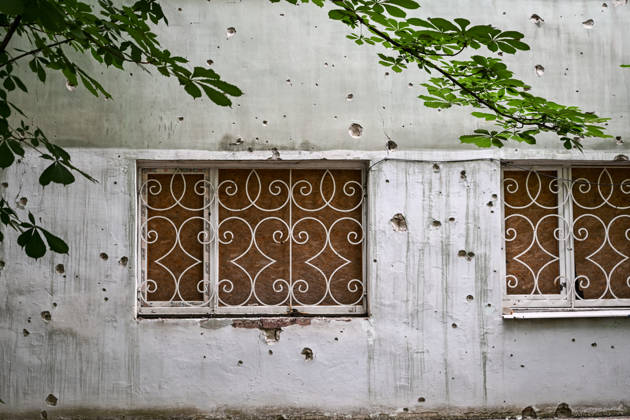RECORD DATE NOT STATED A building damaged by shrapnel from Russian attacks is seen in the frontline city of Kherson, Ukraine, on June 2, 2026. The Russian army attacks the city daily with FPV drones and other unmanned aerial vehicles, deliberately terrorizing civilians. Russian forces conduct hunts for local residents, tracking them with FPV drones and dropping explosives. Police officers, medics, public transport, and urban infrastructure are also targeted. Based on the intensity of attacks, Kherson is informally divided into yellow and red zones, with the red zone considered the most dangerous due to constant shelling and drone strikes. Anti-drone netting has been installed above roads to help protect against Russian FPV drone attacks (Photo by Dmytro S Copyright: xDmytroxSmolienkox