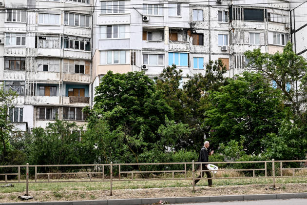 RECORD DATE NOT STATED A man walks past a residential building damaged by Russian shelling in the frontline city of Kherson, Ukraine, on June 2, 2026. The Russian army attacks the city daily with FPV drones and other unmanned aerial vehicles, deliberately terrorizing civilians. Russian forces conduct hunts for local residents, tracking them with FPV drones and dropping explosives. Police officers, medics, public transport, and urban infrastructure are also targeted. Based on the intensity of attacks, Kherson is informally divided into yellow and red zones, with the red zone considered the most dangerous due to constant shelling and drone strikes. Anti-drone netting has been installed above roads to help protect against Russian FPV drone attacks (Photo by Copyright: xDmytroxSmolienkox