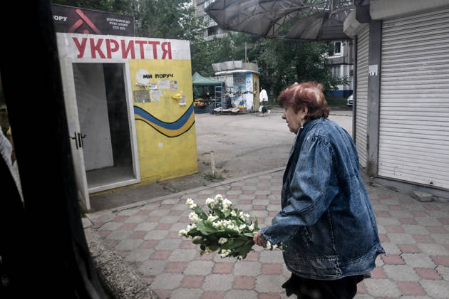 RECORD DATE NOT STATED A woman carrying a bouquet of mock-orange blossoms walks past a mobile concrete shelter in the frontline city of Kherson, Ukraine, on June 2, 2026. The Russian army attacks the city daily with FPV drones and other unmanned aerial vehicles, deliberately terrorizing civilians. Russian forces conduct hunts for local residents, tracking them with FPV drones and dropping explosives. Police officers, medics, public transport, and urban infrastructure are also targeted. Based on the intensity of attacks, Kherson is informally divided into yellow and red zones, with the red zone considered the most dangerous due to constant shelling and drone strikes. Anti-drone netting has been installed above roads to help protect against Russian FPV dron Copyright: xDmytroxSmolienkox