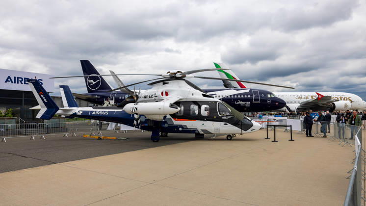 Trade visitor day at ILA Berlin 2026, Berlin, 12 06 2026 The Airbus Racer F WRAC , a high-speed demonstration helicopter from Airbus Helicopters, stands in the outdoor area of the aviation trade fair An Airbus A320neo in Lufthansa livery and an Emirates wide-body aircraft can be seen in the background Schöneberg Berlin ExpoCenter Airport Brandenburg Germany 20260612-286A9690-M4000